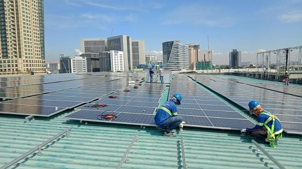 Solar panel workers installing photovoltaic panels on Festival Mall rooftop for sustainable energy.